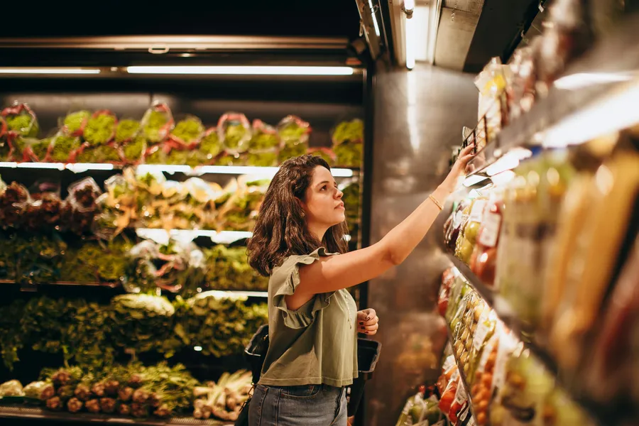 Woman selecting products at a grocery store shelf